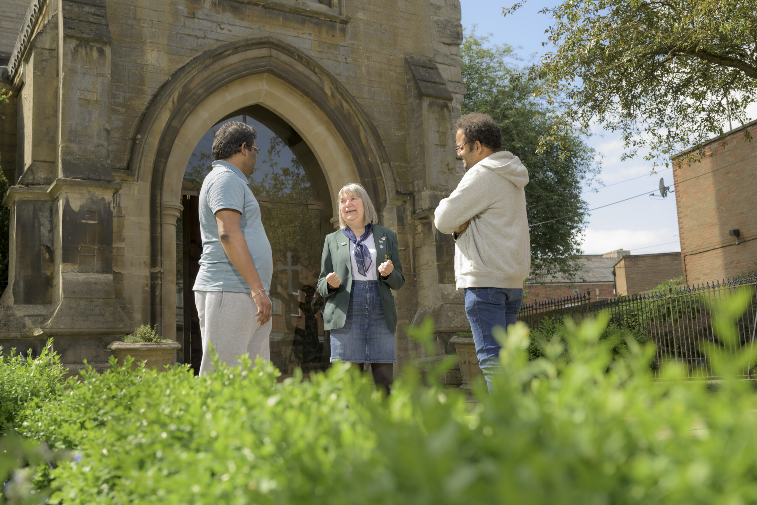 Small group chatting outside a stone church with a Gothic arched doorway on a heritage walking tour