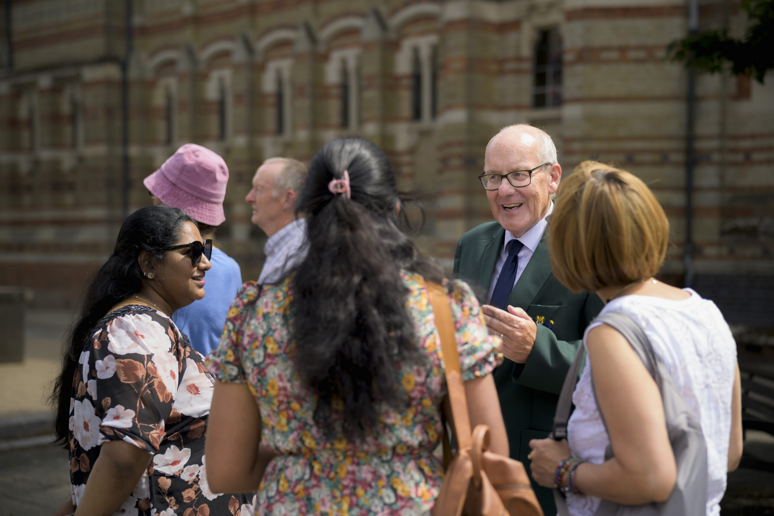 Tour guide in a blazer talking with a group of visitors outside an ornate town-centre building