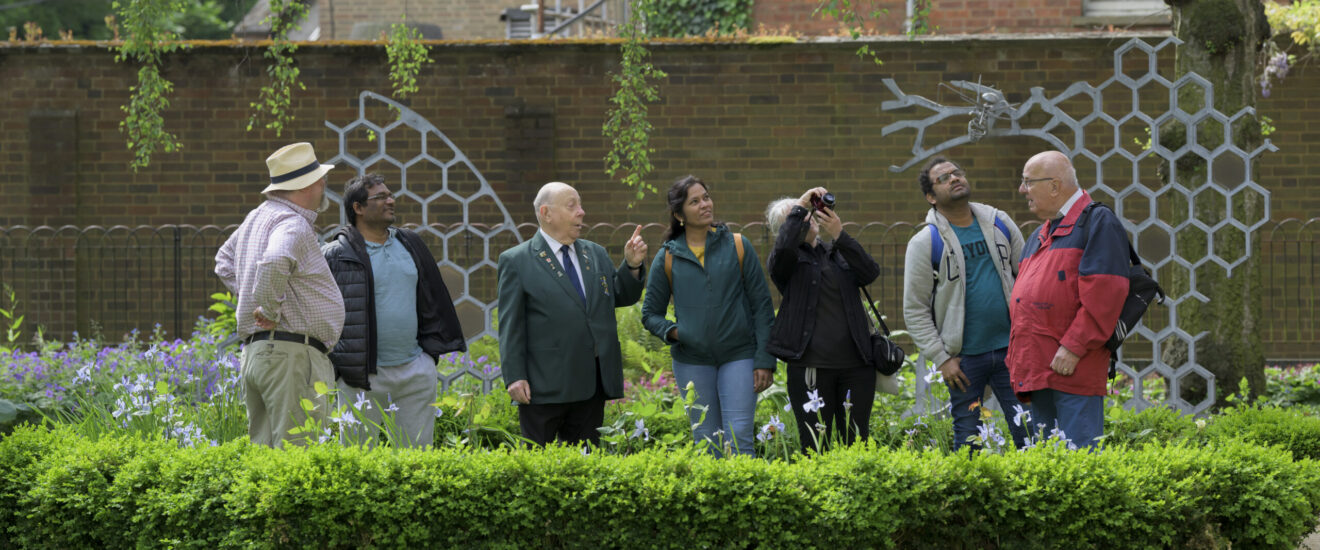 Guide leading a group of visitors beside the honeycomb and bee sculptures on a town tour