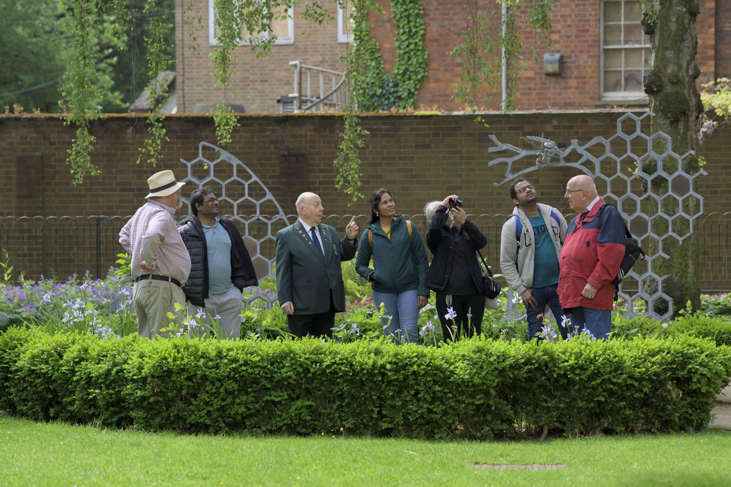 Guide leading a group of visitors beside the honeycomb and bee sculptures on a town tour