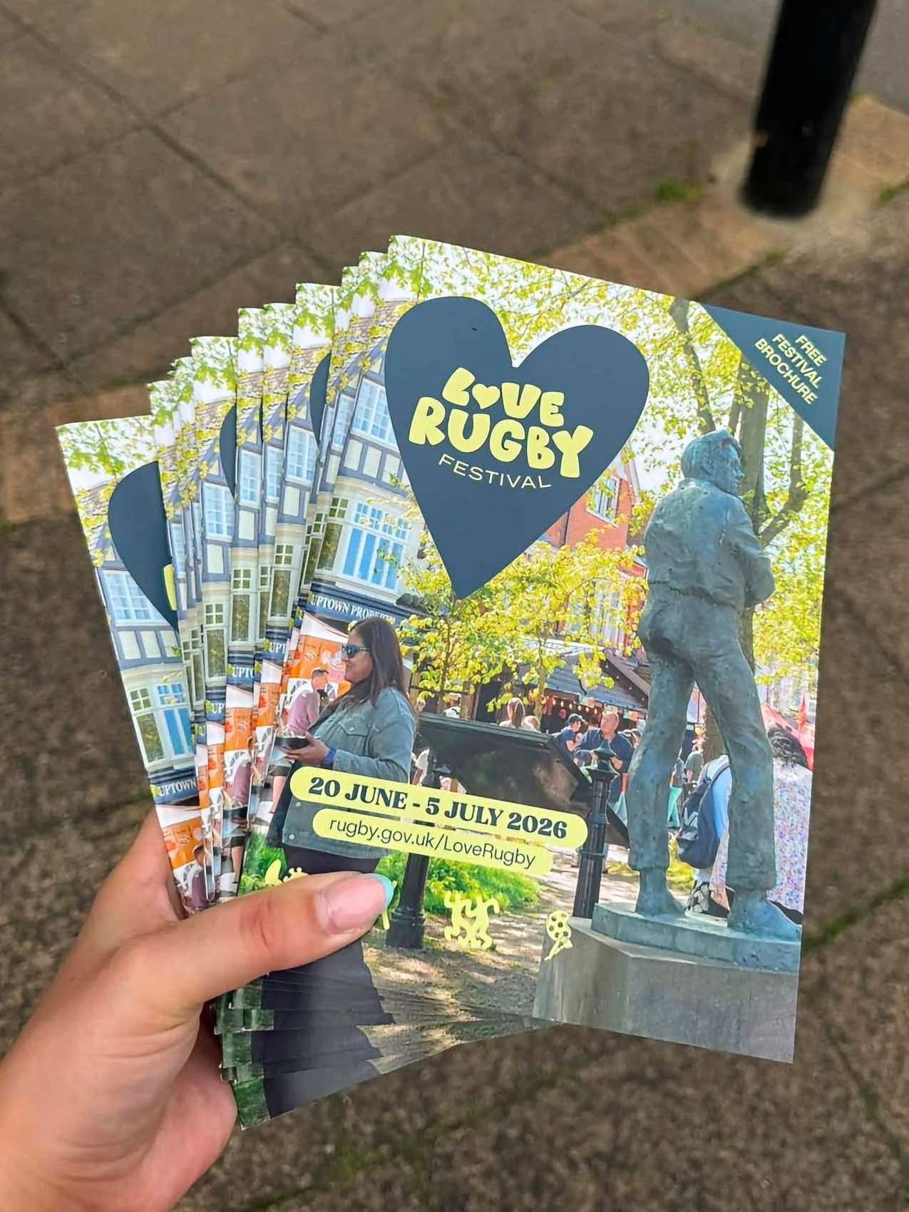 Hand holding Love Rugby Festival brochures dated 20 June to 5 July 2026