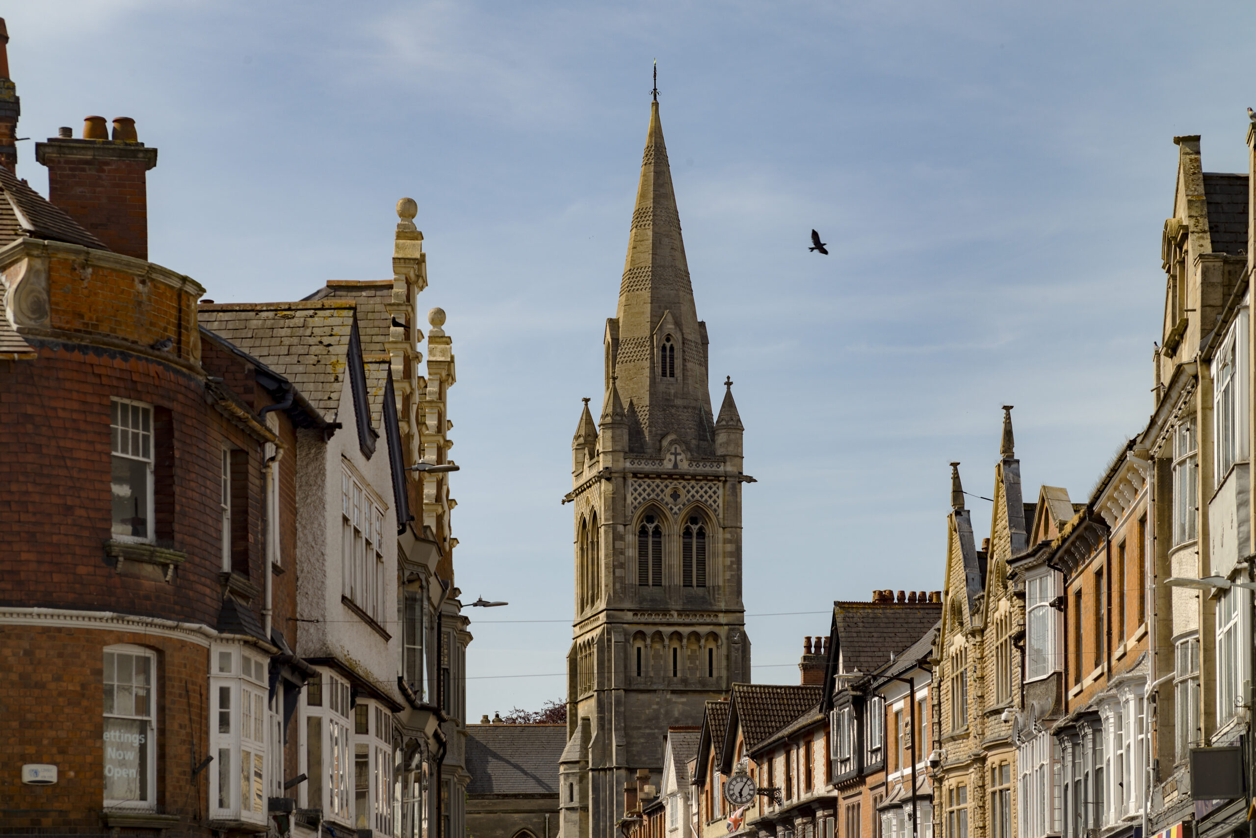 View along a town-centre street towards the tall spire of St Andrew's Church