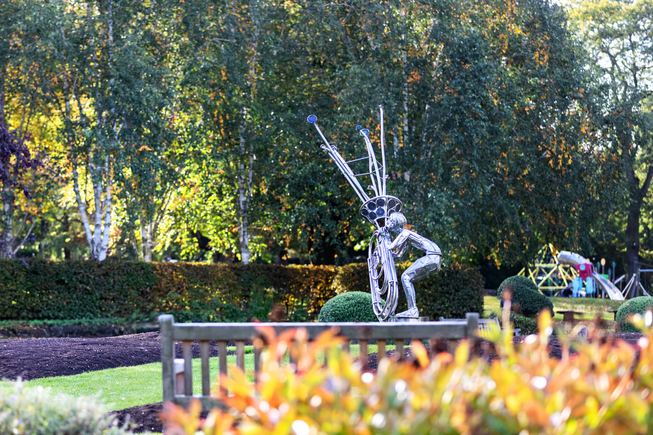 Wire mesh figure sculpture in a park bed of autumn heather and flowers