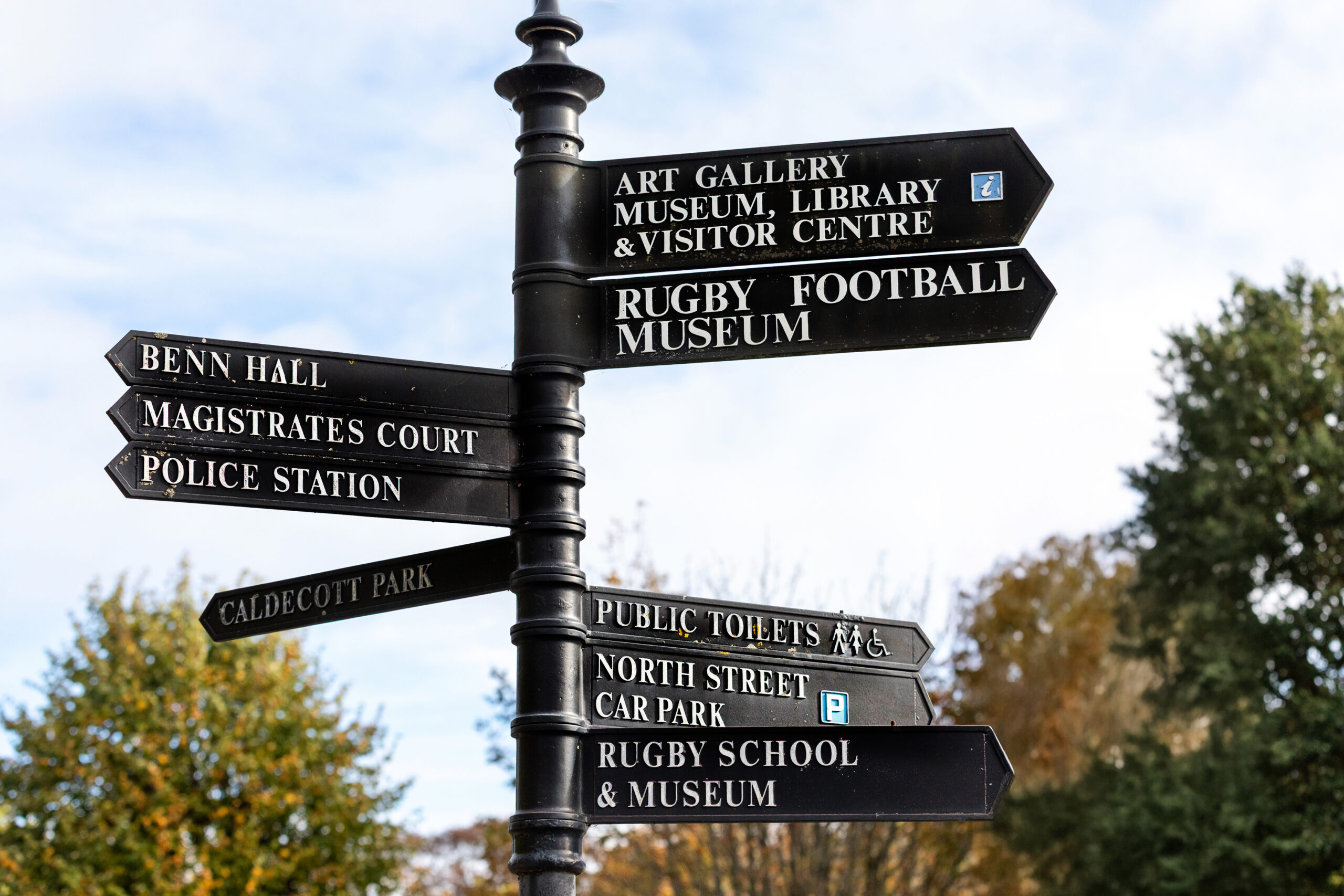 Cast-iron fingerpost signpost pointing to town attractions including the Art Gallery, Rugby Football Museum and Rugby School