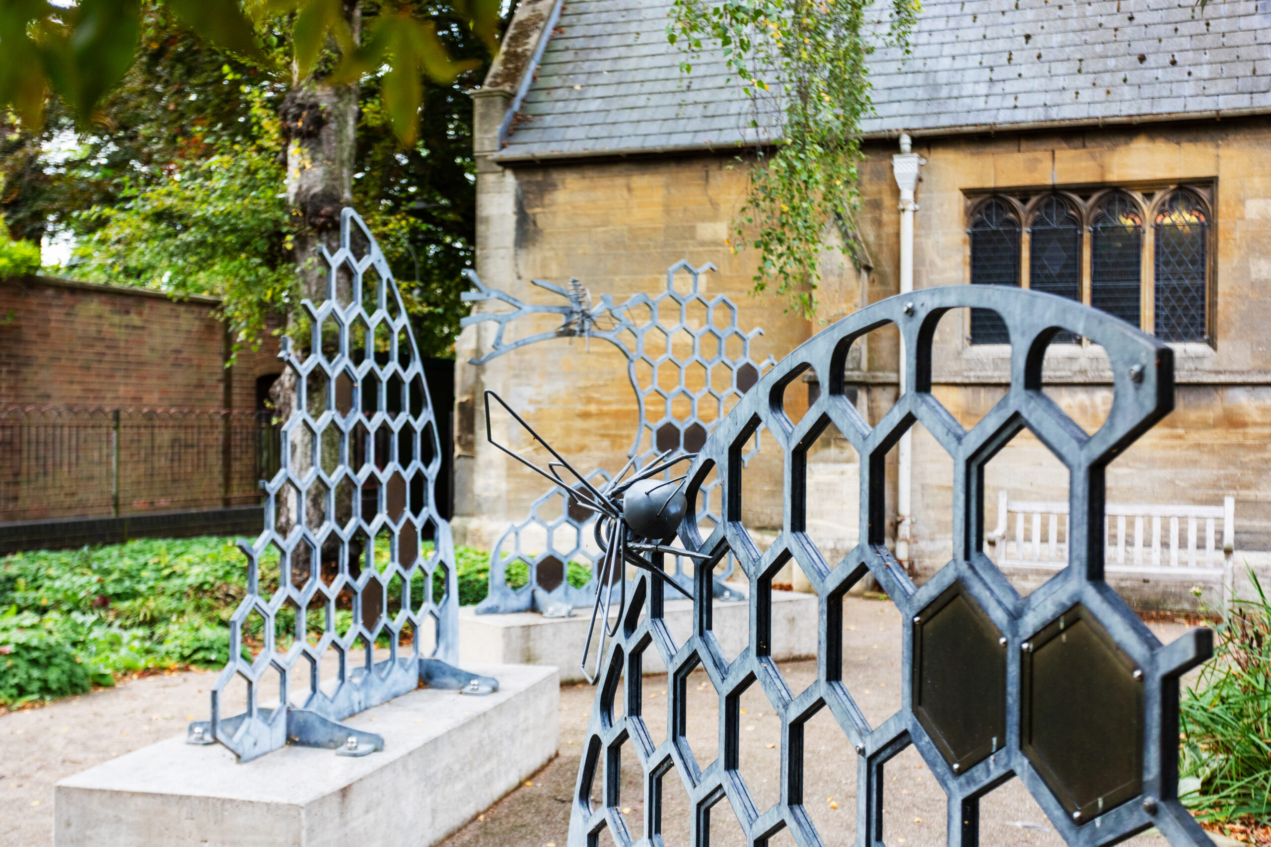 Modern honeycomb and bee sculptures outside a stone church