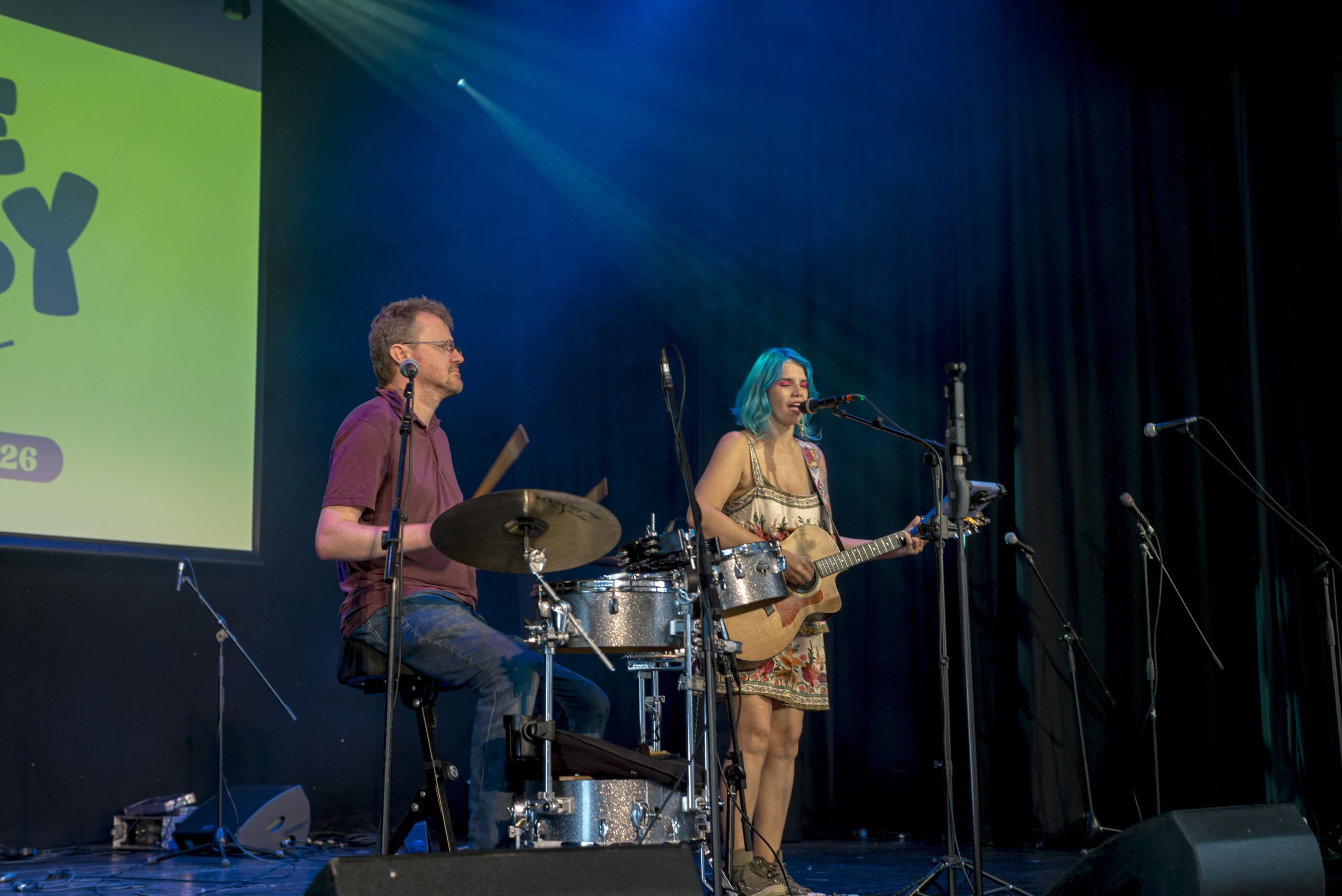 Two musicians performing live on a darkened stage lit with green light