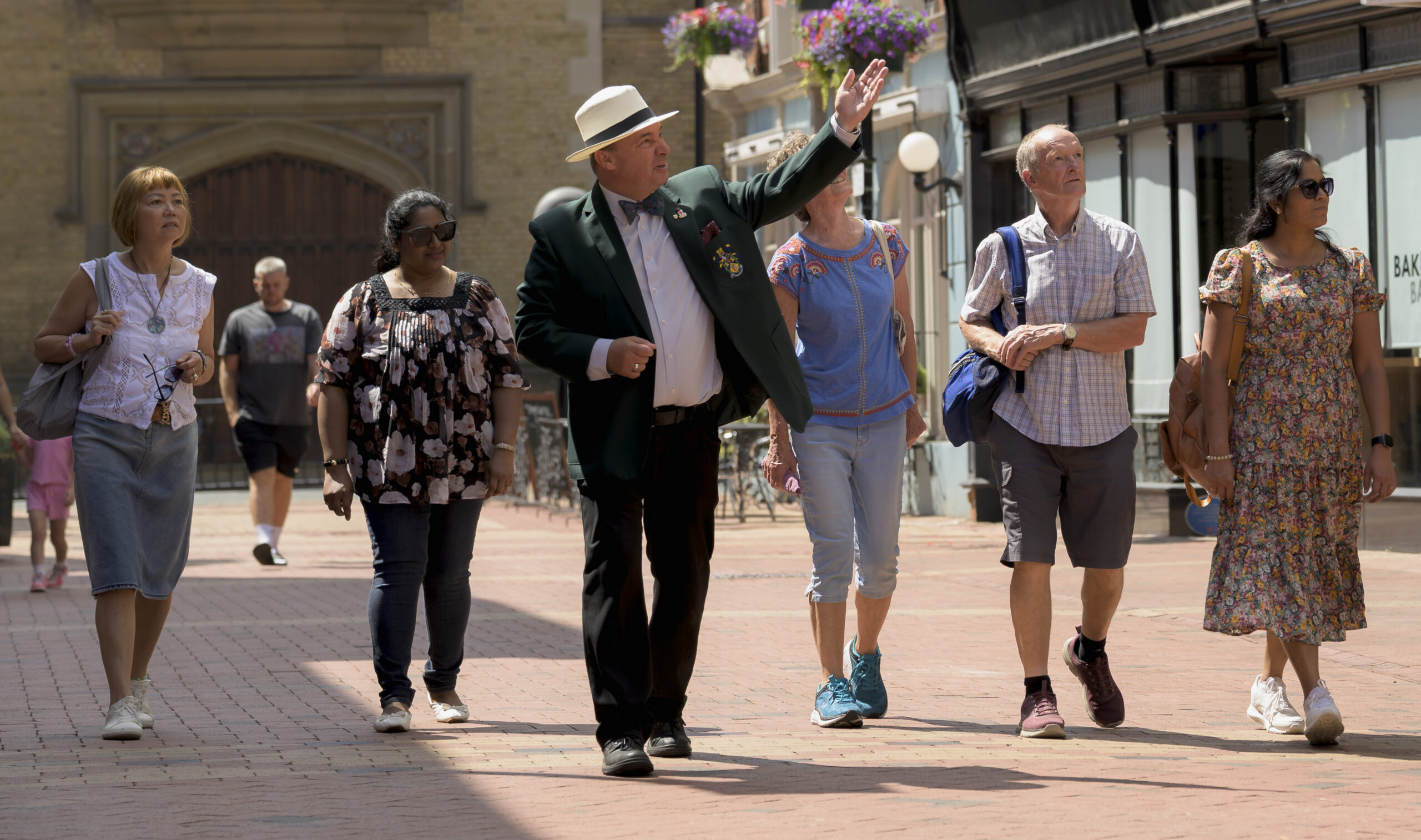Guide in a boater hat leading a group of visitors on a walk through the pedestrianised town centre