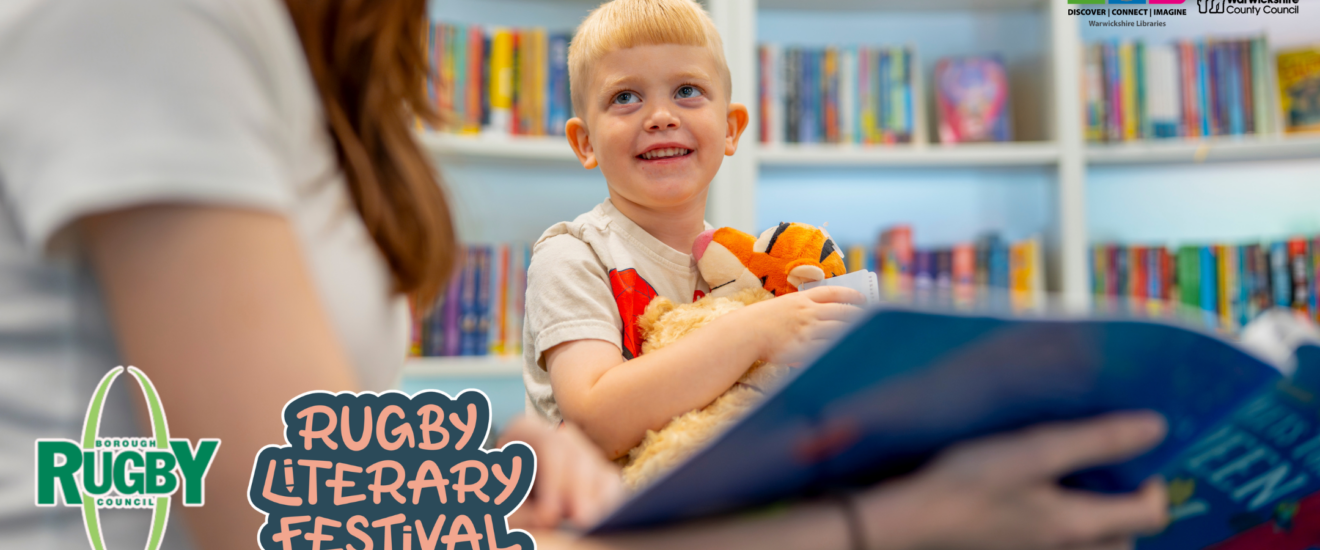 Woman holding picture book reading to a smiling child who is hugging a tiger teddy bear.