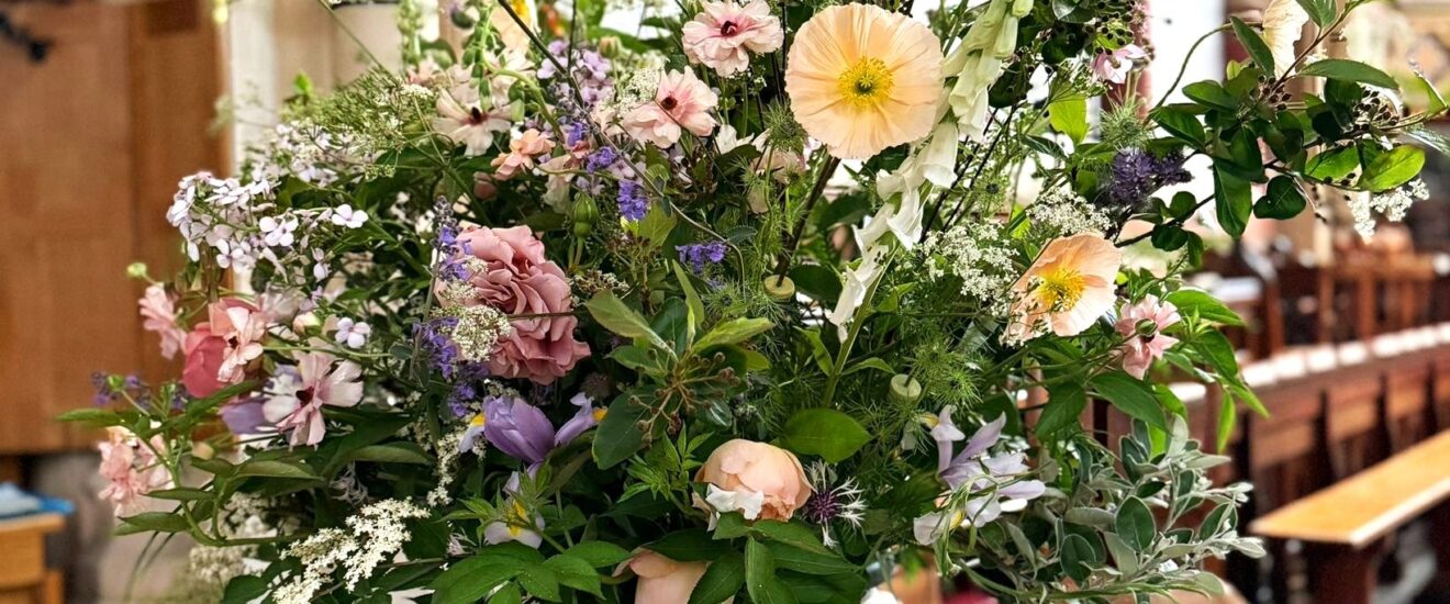 floral arrangement in white urn with a church in the background