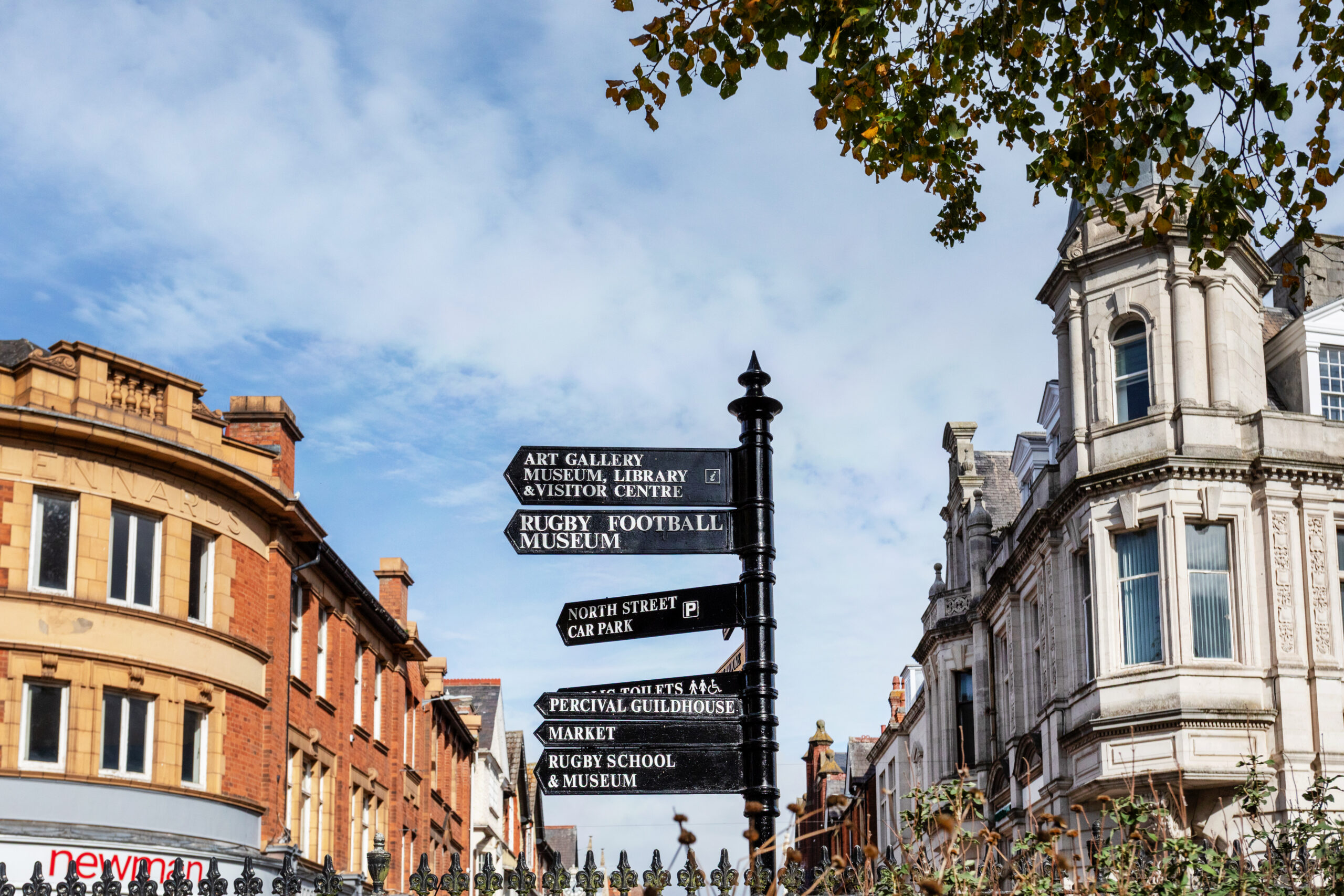Black cast-iron direction signpost at a junction in front of ornate Victorian town-centre buildings