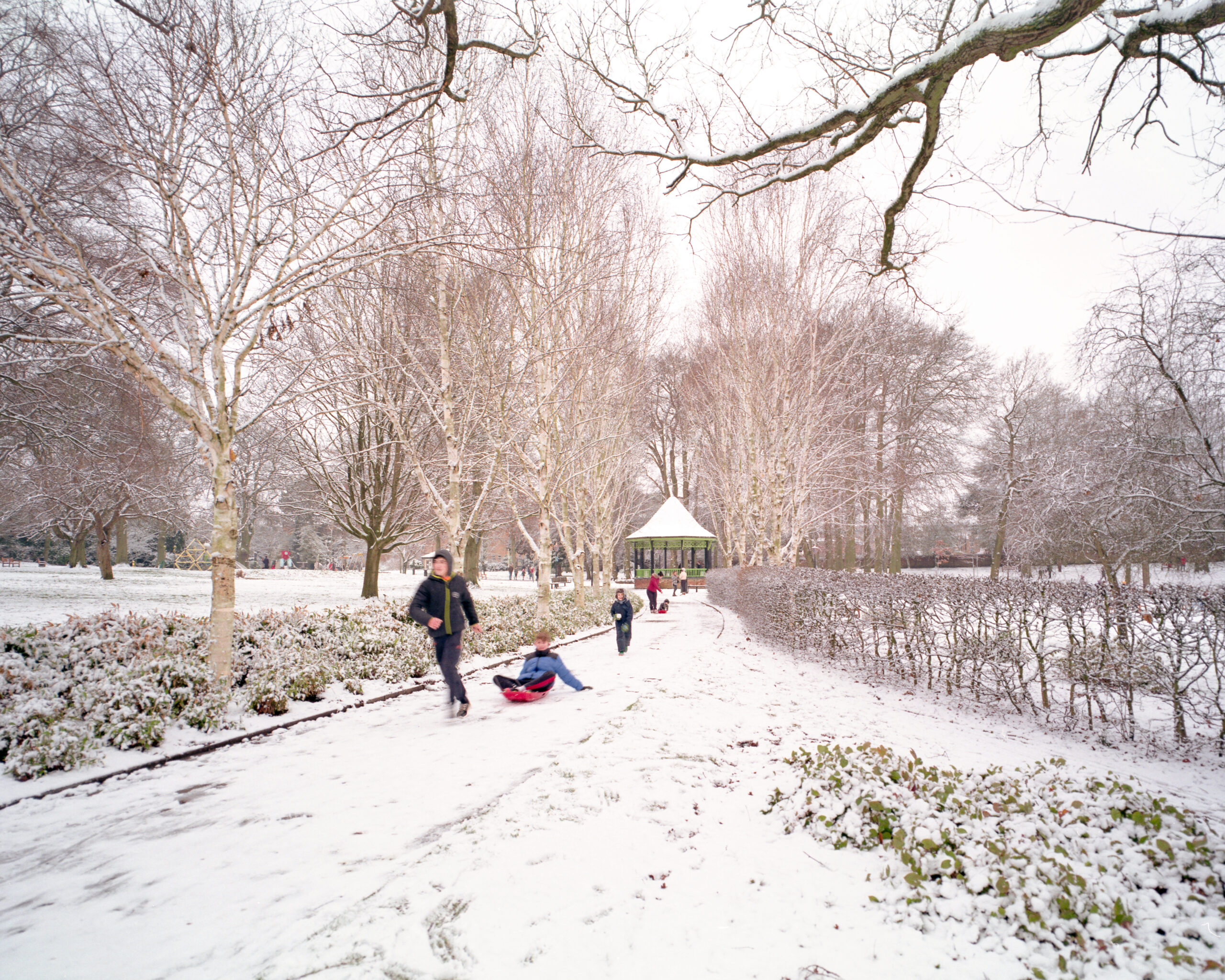 Children pulling and playing on sledges in a snow covered park
