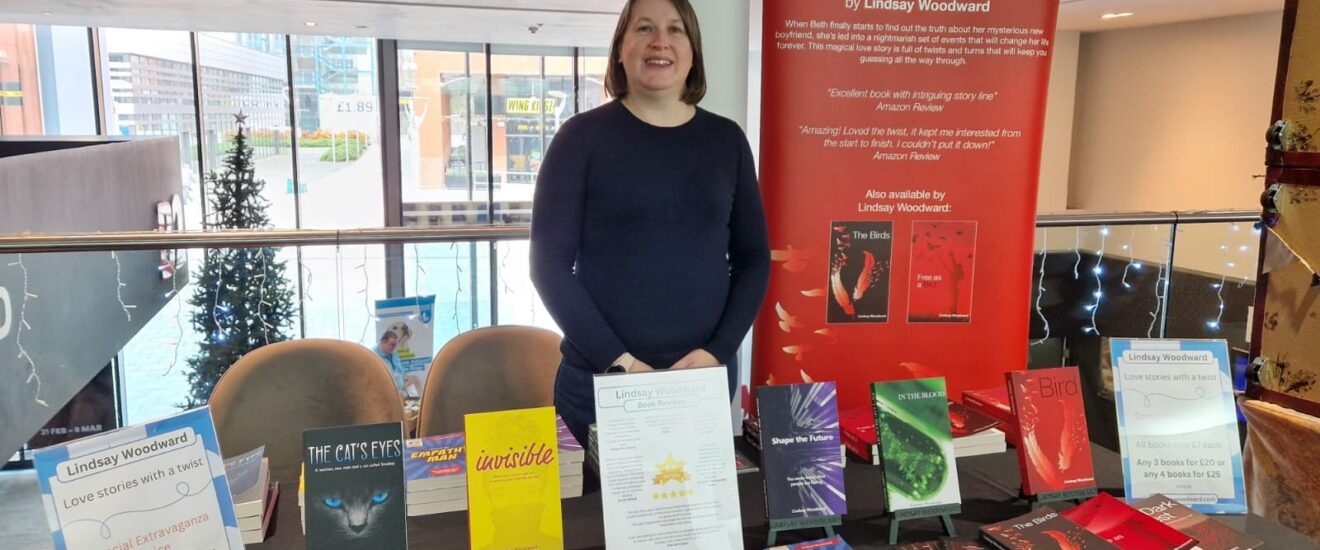 Woman stood behind table with books on it.