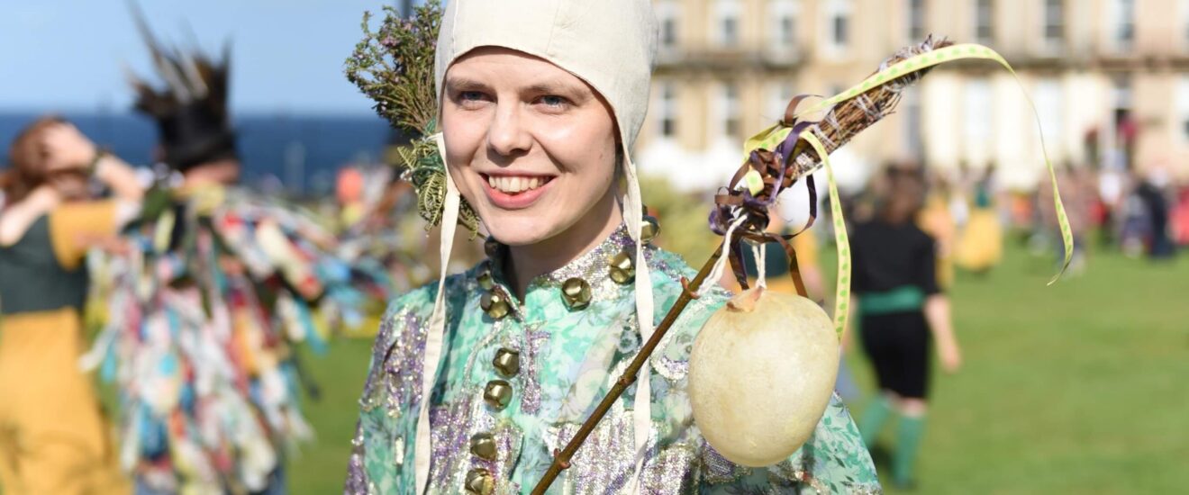 Person on a lawn in costume with a marottes.